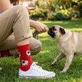 Woman in a garden with a pug, wearing red socks with pug pattern.